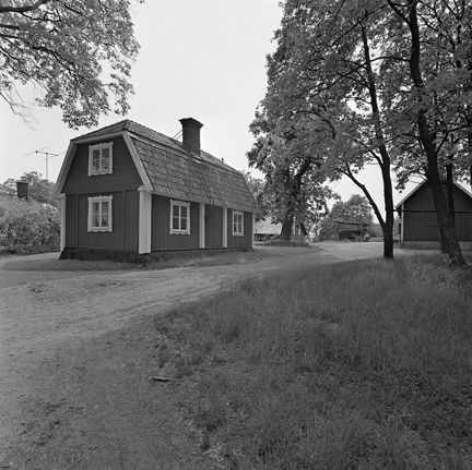 Svartvitt foto på rödmålat(?) torp med vita knutar.