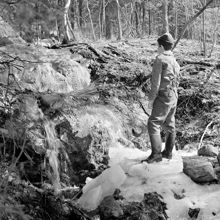 Pojke ute i skogsparti. Berg med smältvatten