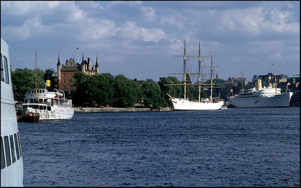 Vy mot Skeppsholmen. Till vänster en Waxholmsbåt, af Chapman ligger vid kaj och i bakgrunden syns ett stort passagerarfartyg.