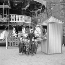 Kungsträdgården. Tivoli/karusell i samband med Röda Korset-veckan. En kvinna med en grupp barn vid biljettkassan