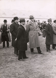 Kristinebergs Idrottsplats invigs. Män i överrock och hatt lyssnar på invigningstalet. 25 maj 1933