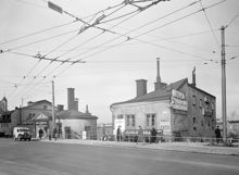 Kv. Järngraven Övra före rivning. T.v. Södermalmstorg 26 och t.h. Västra Slussgatan 10. Trådbussledningar hänger över gatan. Kvarteret låg mellan Sjöbergsplan och Södermalmstorg