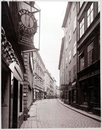 Folktom gränd. Rund butiksskylt, "Alpacca Silfver".