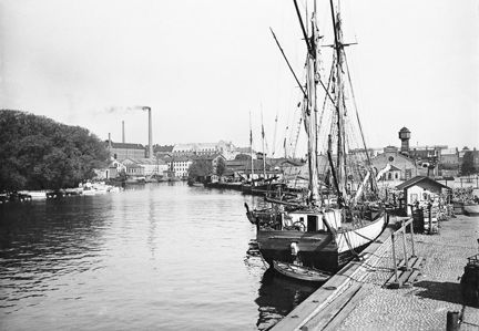 Vi ser Klara sjö med båtar längs kajerna vid Klara strand och i bakgrunden fabriksbyggnaderna vid bolinders verkstäder.