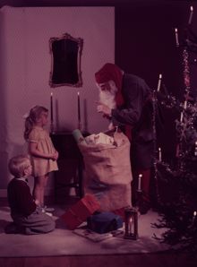 Reklamfoto för stearinljus i juletid. Tomten kommer med julklappar. 