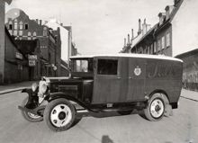 Reklambild för bil från Ostermans, på stockholmsgata. Bilen bär märket Sabis (Slakteriaktiebolaget i Stockholm).