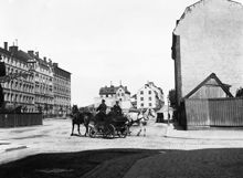 Två hästfordon passerar varandra i hörnet av Hornsgatan och Ringvägen. T.v. Ringvägen 4-2. I bakgrunden går Yttersta Tvärgränd norrut mot Skinnarviksberget.