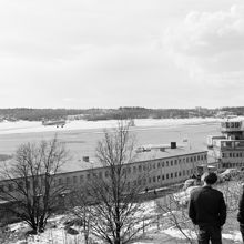 Utsikt från Ranhammarshöjden över Bromma flygplats. Flygplan från Linjeflyg på väg upp i luften. Åskådare i förgrunden.