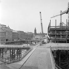 Brunkebergstorg med provisoriska broar i förgrunden. Vattugatan går västerut från Brunkebergstorg 7. T.v. ligger Herkulesgatan. Kv. Wahrenberg och Elefanten är rivna. I fonden ses Stadshuset