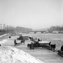 Snöröjning på Strandvägen. Snön tippas i Ladugårdslandsviken från kajkanten. Djurgårdsbron i fonden