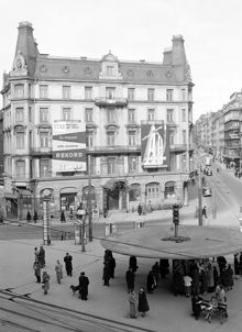 Birger Jarlsgatan och Stureplan med Hotell Anglais. Sturegatan t.h. Över gatan hänger ledningar som ger ström till spårvagnar och trådbussar