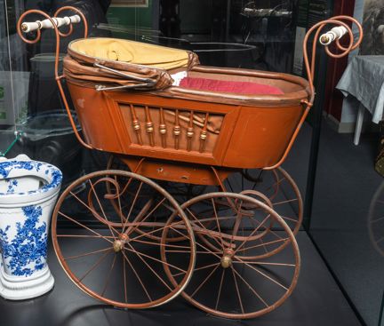 Gammal barnvagn i trä med sufflett och stora hjul