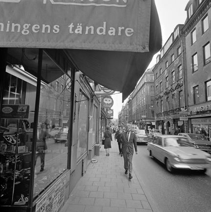 En man på trottoaren.Butiker.