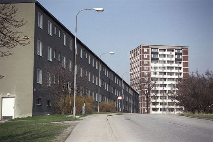 Gatuvy med en lägre bostadslänga och ett höghus.