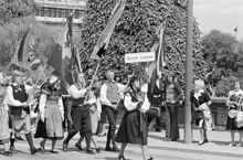 Reportage kring Kungabröllopet den 19 juni 1976. Fanbärare i täten för spelmanslag tågar över Norrbro. Främst går en kvinna med skylten ""Gustafs kompani""