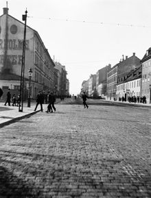 En grupp män passerar Hornsgatan vid hörnet av Rosenlundsgatan. T.v. Hornsgatan 59-61. T.h. Hornsgatan 84 västerut