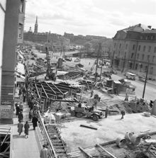 Vasagatan. Vy mot Tegelbacken och Riddarholmen. T.v. pågår arbete med att däcka över tunnelschaktet för tunnelbanan. T.h. Centralstationen