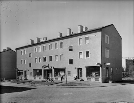 Ett flerfamiljshus i två våningar med en livsmedelsbutik och två mindre butiker i bottenvåningen.