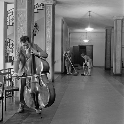 En kontrabasist. Två städerskor i bakgrunden.