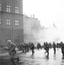 Stridsövningar på Riddarholmen. I skydd av utlagda rökridåer rusar stormbåtstrupper fram på Södra Riddarholmshamnen, mot Birger Jarls torg