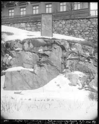 Kalvariestenen i sin järnram uppe på en bergsknalle på Pelarbacken. Svartvitt foto.