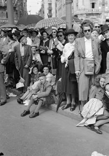 Nybroplan. Folk kantar vägen i samband med firandet av kung Gustaf V:s 90-års dag