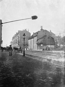 Hästfordonen svänger av från Hornsgatan mot Ringvägen. Hornsgatan 104-106 (kv. Tapeten) står inför rivning och Hornsgatan 108-116 (kv. Uven Mindre) byggdes 1901. Hornsgatan västerut. Nu kv. Tapeten